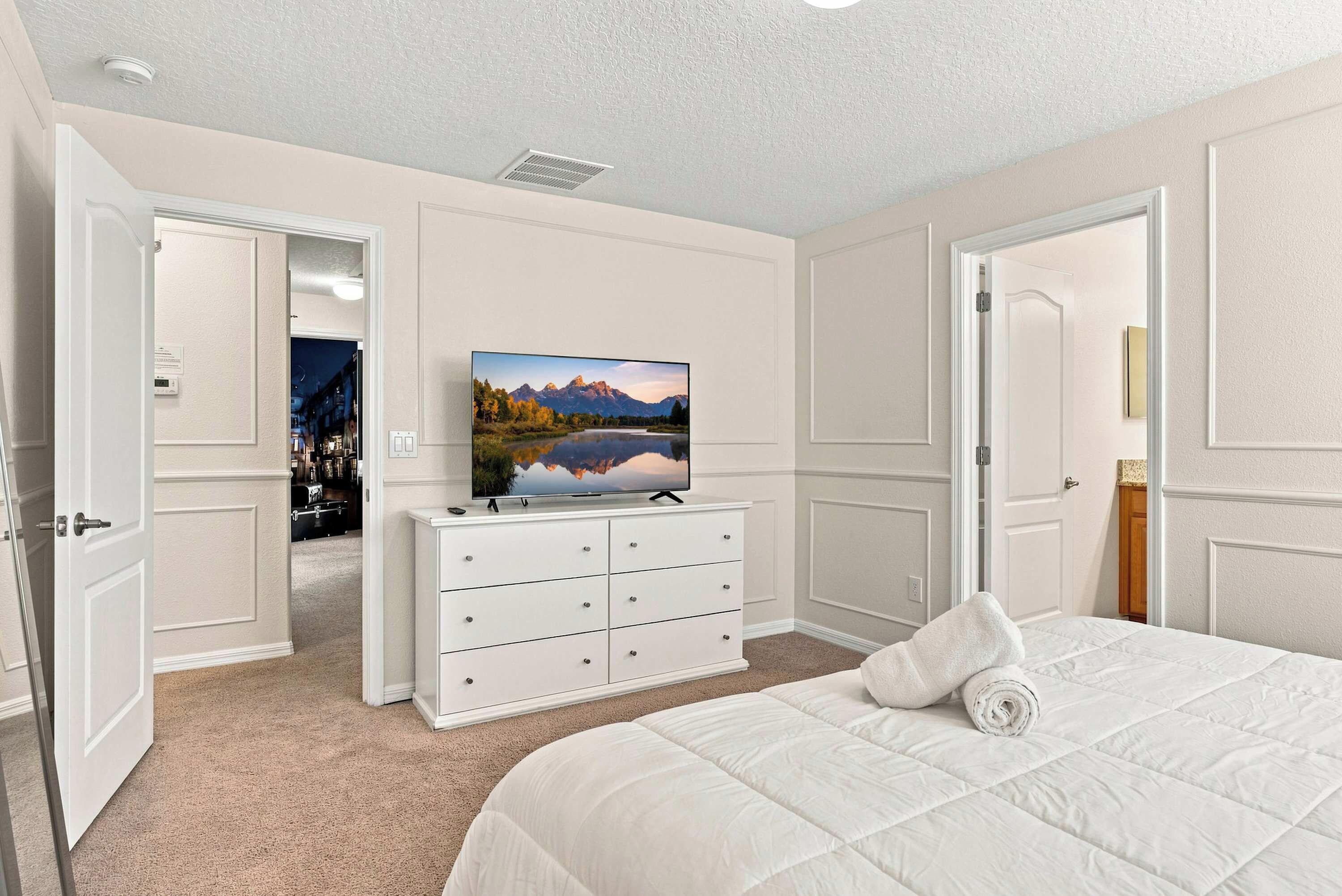 A hotel room with a bed, a television on a dresser, and a view of a mountain landscape.