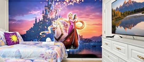 A bedroom with a large mural of a castle and a character, a bed with floral bedding, and a TV on a dresser.