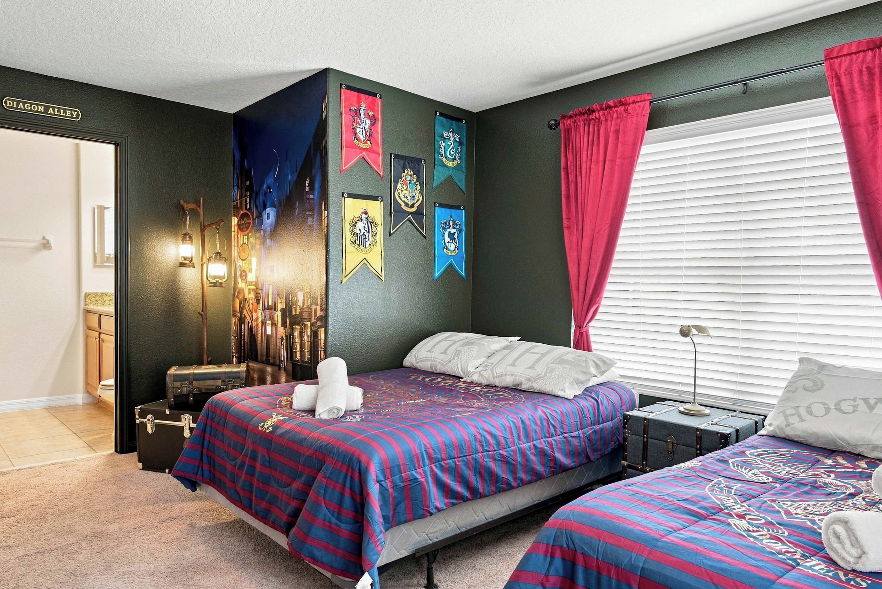 A bedroom with two beds, a nightstand, a lamp, and a window with curtains.