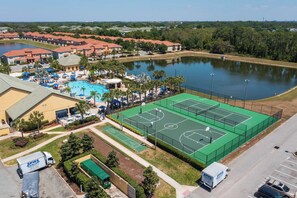 A residential area with a swimming pool, tennis courts, and a large body of water. - Family-friendly Paradise Palms Townhouse With Pool Access (Kissimmee)