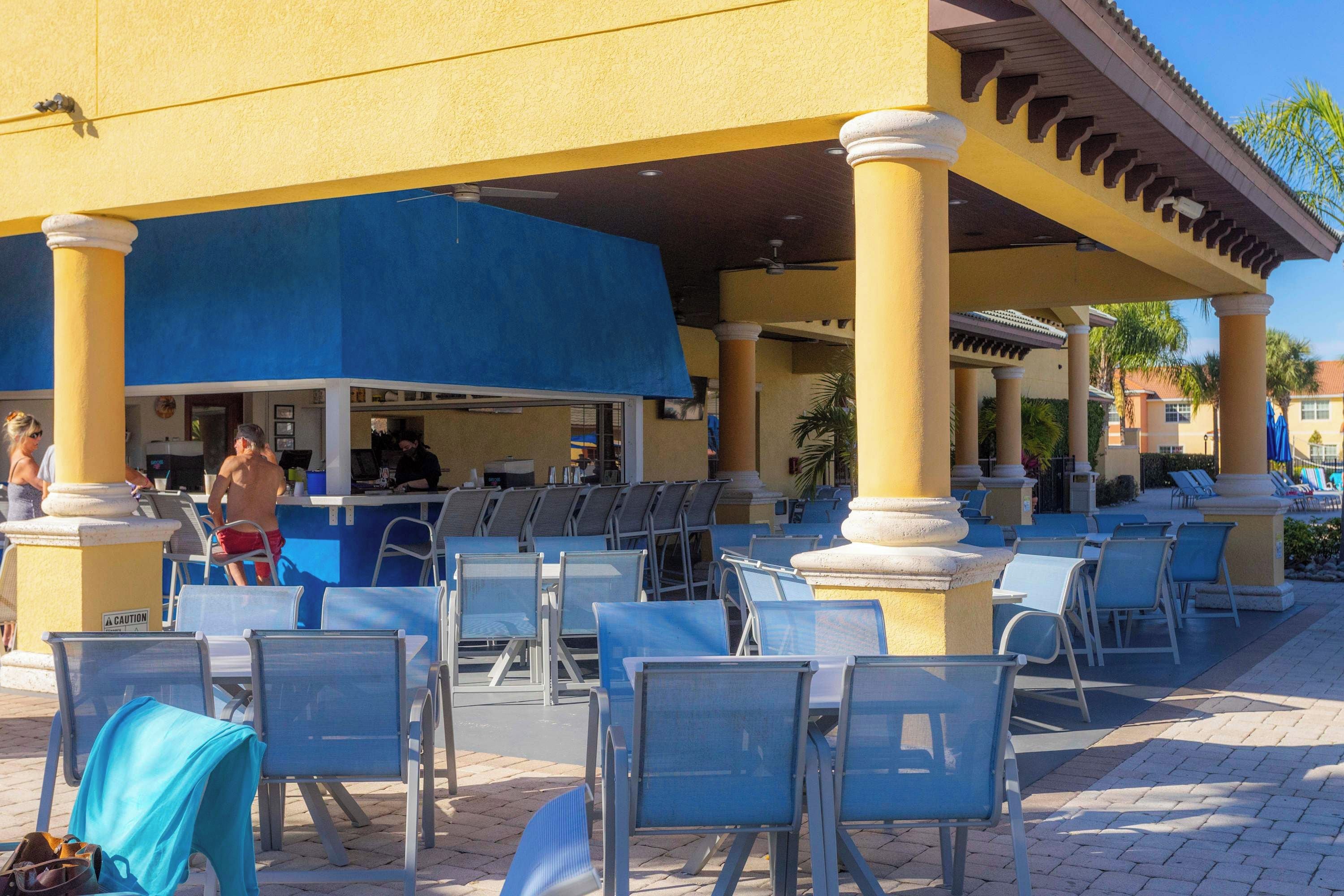 An outdoor seating area with blue chairs and a covered section with a bar.
