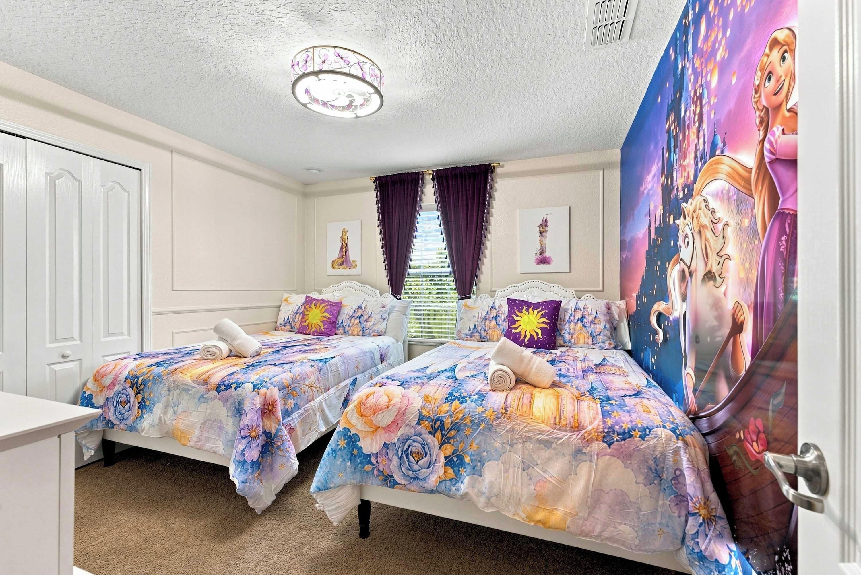 A bedroom with two beds, each with floral bedding, a ceiling light fixture, and a large poster on the wall.