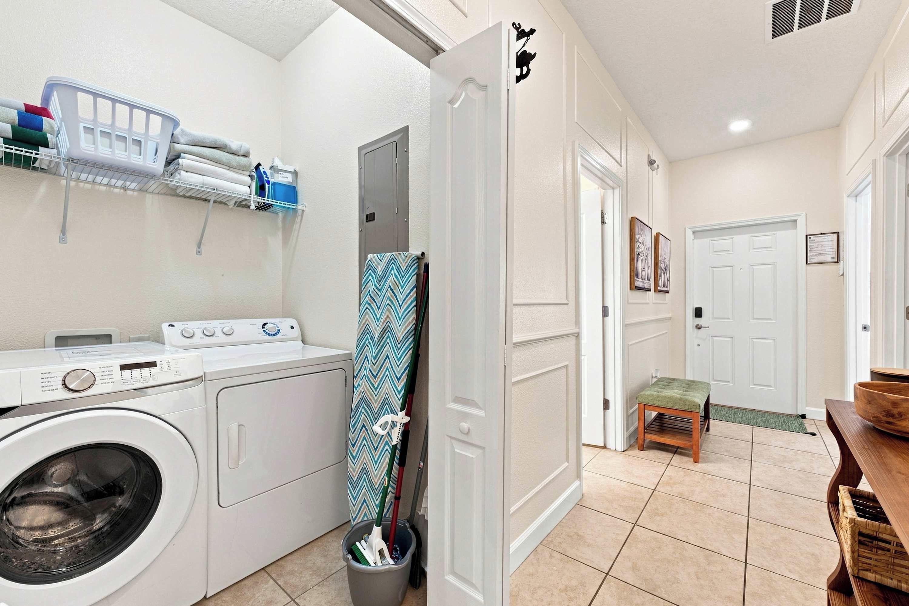 A laundry room with a washing machine, a drying rack, and a bucket with cleaning tools.
