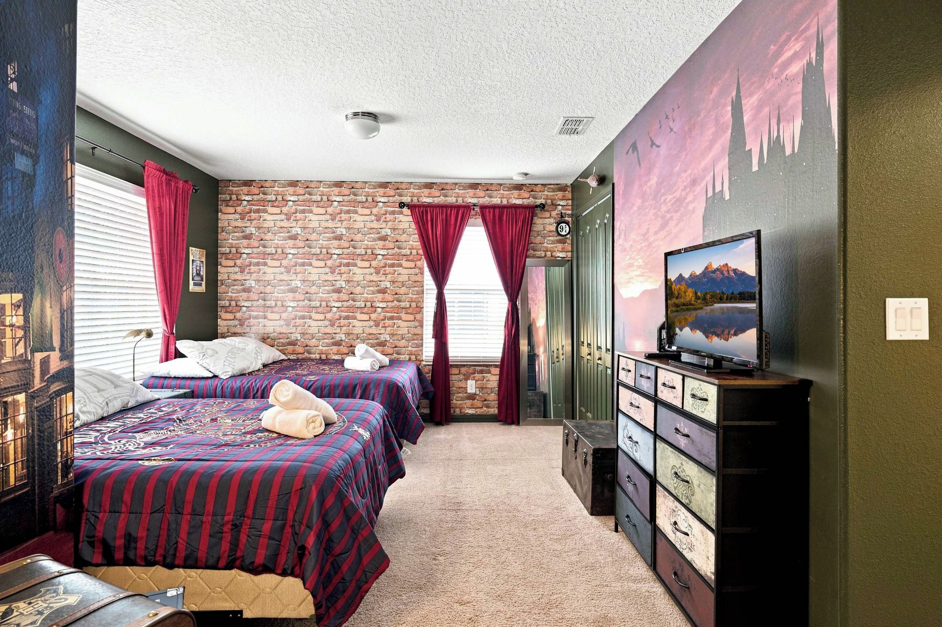 A room with two beds, a brick wall, a television, and a dresser.