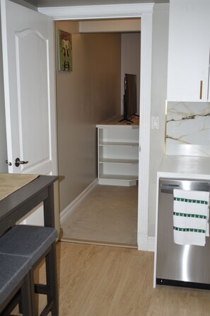 Une cuisine équipée d’un plan de travail, d’un évier et d’une porte donnant sur un couloir.