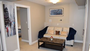 A living room with a sofa, a coffee table, and a painting on the wall.