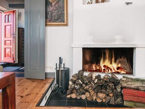 A fireplace with logs, a door, and a painting on the wall. - 5 Star Holiday Home in Fano (Fano)