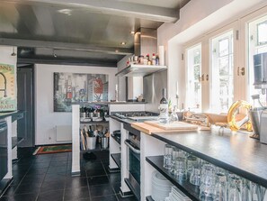 A modern kitchen with a central island, a painting on the wall, and a view of the outdoors through large windows. - 5 Star Holiday Home in Fano (Fano)