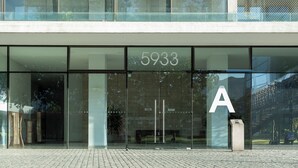 Ein Gebäude mit großen Glasscheiben, einer sichtbaren Nummer 5933 und einem Buchstaben 'A' auf der rechten Seite.