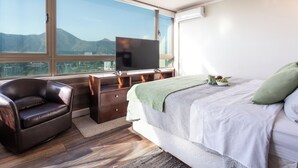 Ein Schlafzimmer mit Bett, Schreibtisch, Stuhl, Fernseher und Blick auf die Berge.