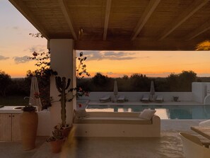 A poolside lounge area with a view of the sunset, a cactus plant, and a white sofa. - Beautiful villa with private pool and breathtaking view, enjoy in southern Italy! (Ostuni)
