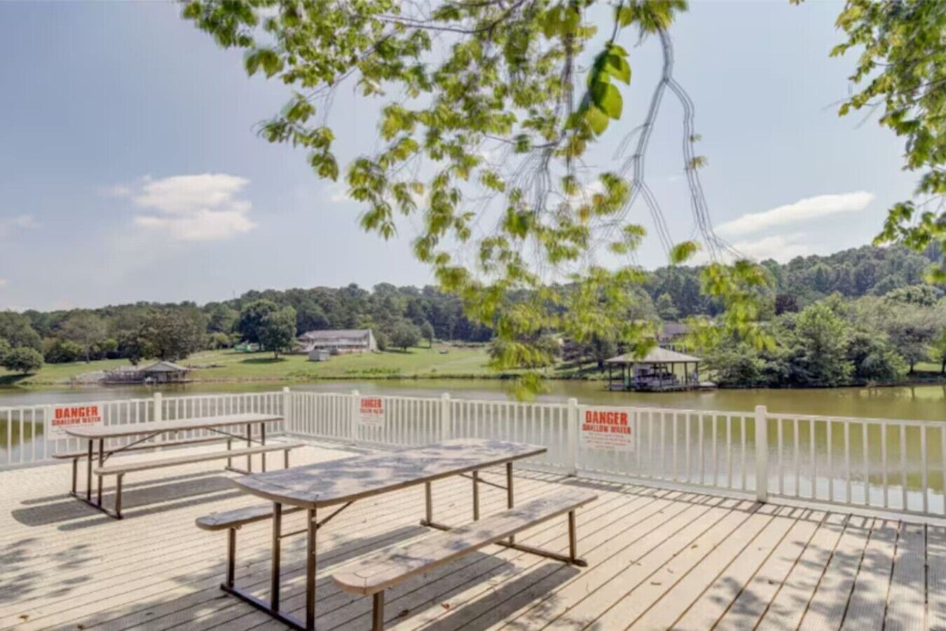 A wooden deck with picnic tables and a view of a lake and forest.