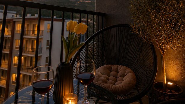 Ein Balkon mit Tisch, Stühlen, einer Blumenvase und einer Kerze.