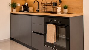 Eine moderne Küche mit dunklen Schränken, einer Holzarbeitsplatte, einem eingebauten Backofen und einer Kaffeemaschine.