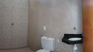 A bathroom with a toilet, a sink, and a shower area. - Pousada Apart Praia Uruau (Beberibe)