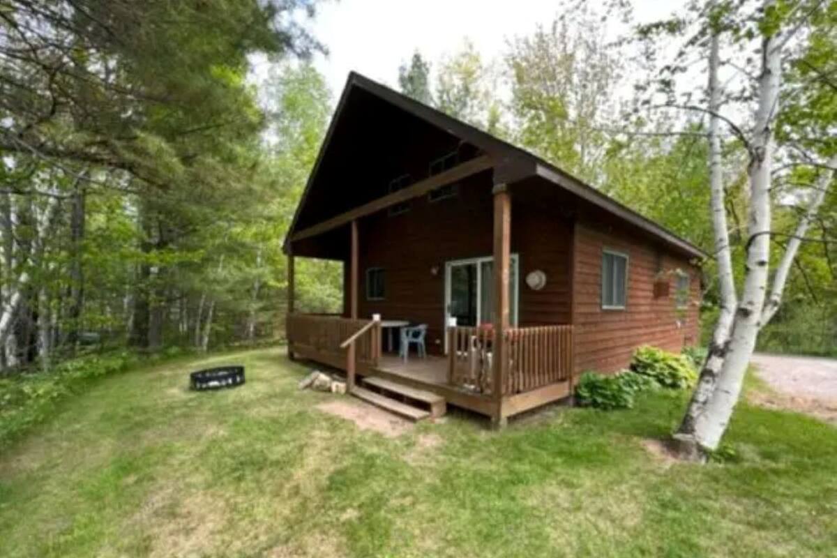 A cabin with a porch, a small table, and a chair.
