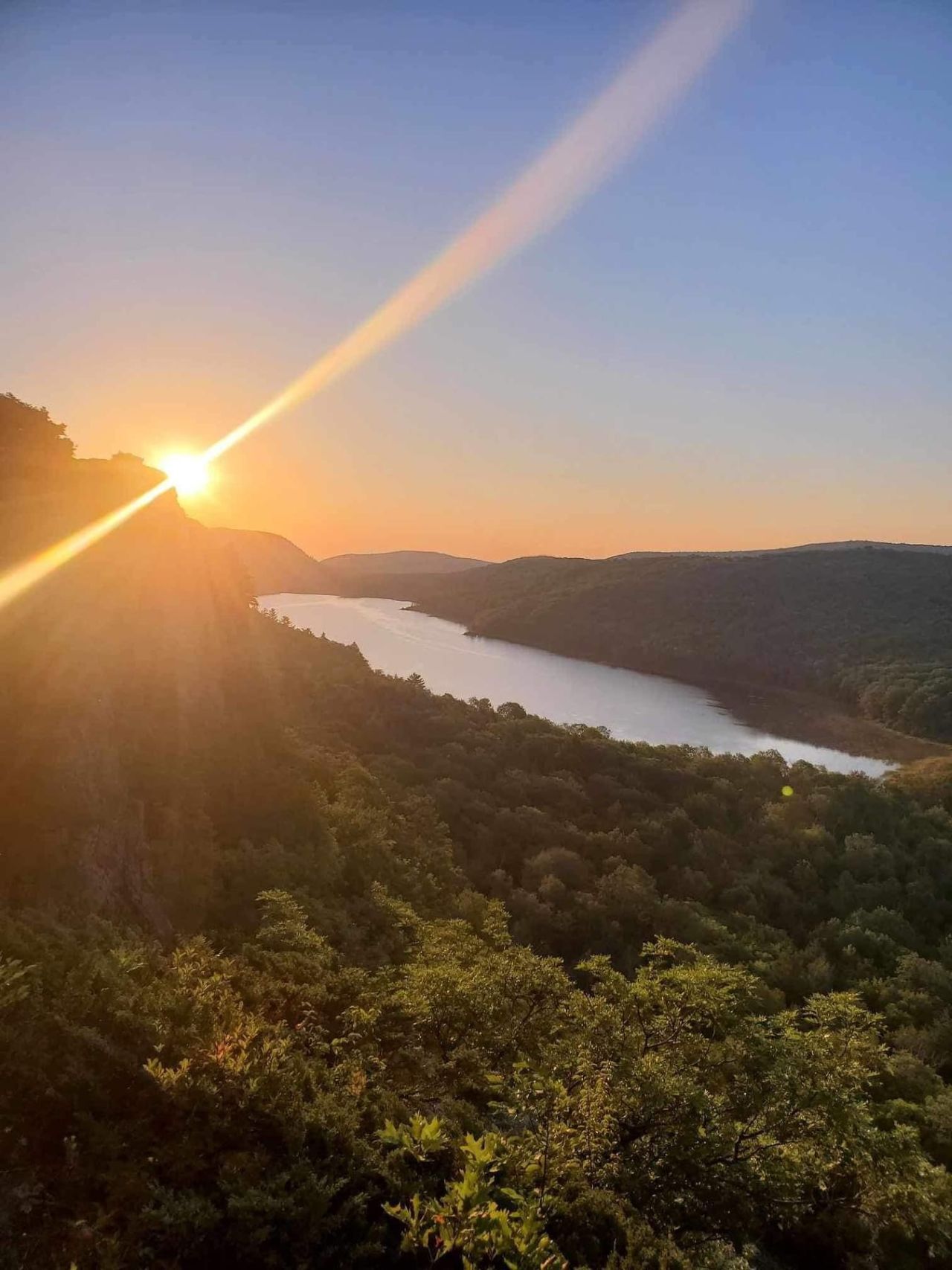 Un valle fluvial con el sol poniéndose tras las colinas.
