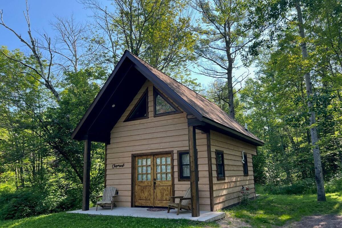 A small cabin with a wooden exterior, a porch with two chairs, and a door labeled 'Cottage.'
