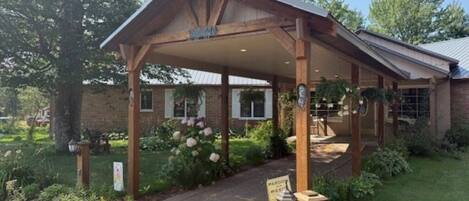 A covered outdoor area with a wooden structure, a sign indicating a wedding venue, and a brick building in the background.