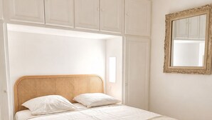 Ein Schlafzimmer mit einem Bett, einem weißen Kleiderschrank und einem Spiegel.