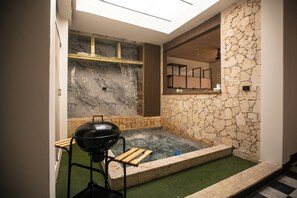 Ein Wellnessbereich mit Whirlpool, Grill und einer Steinwand.