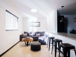 Ein modernes Wohnzimmer mit Sofa, Hocker, Couchtisch und Barhocker.