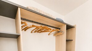 Un vestidor con amplias repisas, una barra para colgar ropa y una pequeña zona de escritorio.