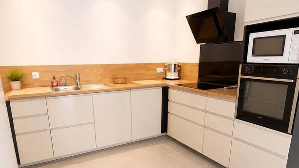 Una cocina moderna con armarios blancos, un microondas, un horno y un lavamanos.
