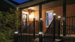 A brick house with a porch, a staircase, and a mailbox.