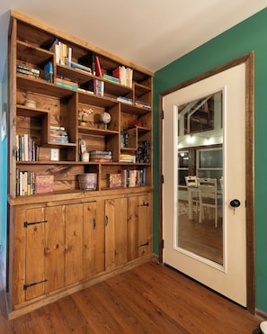 Une bibliothèque en bois contenant divers livres et objets décoratifs, une porte avec un panneau de verre et un plancher en bois.