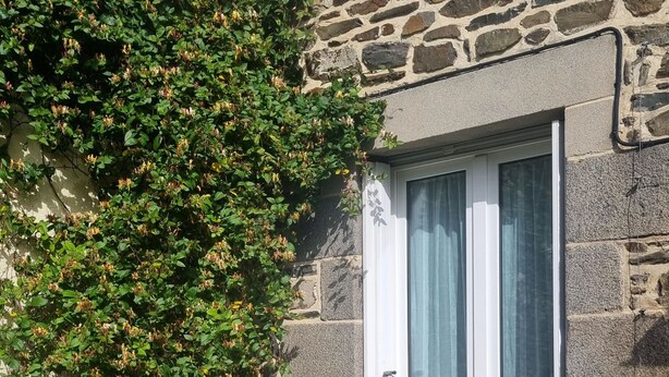 Ein Steinhaus mit Fenster, einer Bank und einem Tisch mit Stühlen.