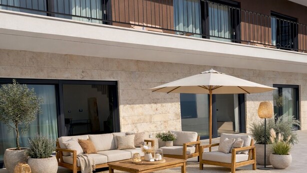 Un área de piscina moderna al aire libre con un conjunto de sofás, una mesa y plantas en macetas.