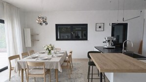 Una cocina moderna con comedor, un ventanal grande y una cafetera.