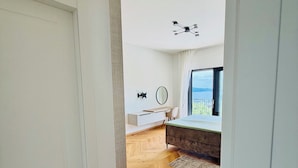 Un interior moderno con suelo de madera de espiga, una cama, un escritorio y un amplio ventanal con vistas.