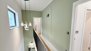 Una escalera con barandal de madera, una lámpara y una puerta al final.