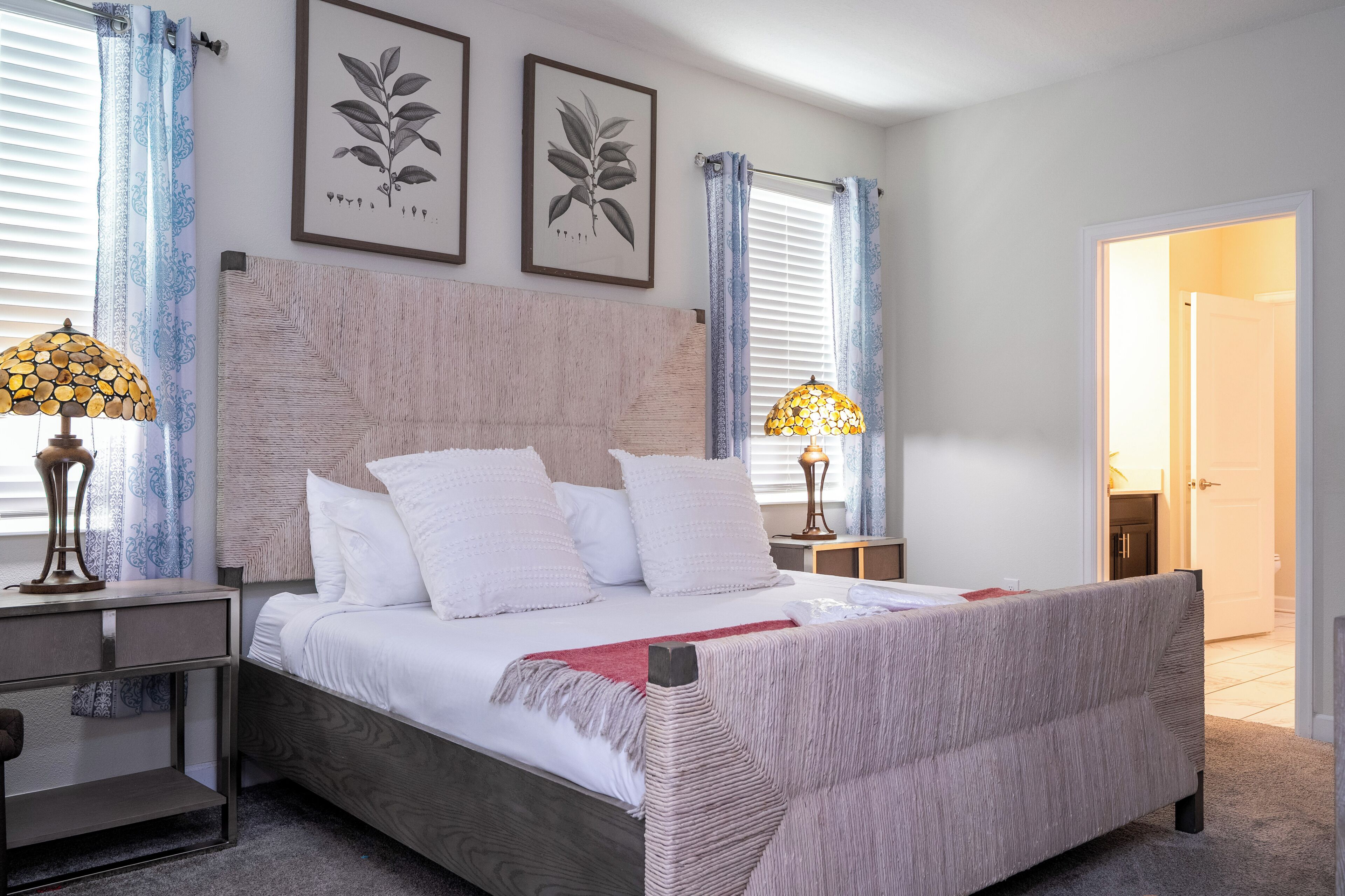 Een keurig opgemaakt slaapkamer met een groot bed, twee nachtkastjes en een bijzettafeltje.