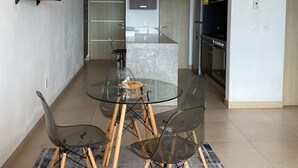 A modern kitchen with a central island, a dining area with a glass table and chairs, and a red sofa. - Apartment in Plaza las Americas tower Montevideo Cancun (Cancún)