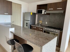Eine moderne Küche mit Granit Arbeitsplatte, Edelstahlgeräten und Holzschränken.