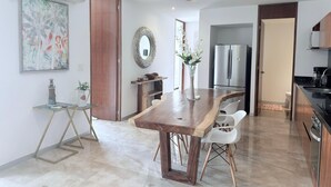 Eine moderne Küche mit Holztisch, weißen Stühlen, einem Edelstahlkühlschrank und einem Deckenventilator.