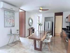 Eine moderne Küche mit Holztisch, weißen Stühlen, einem Edelstahlkühlschrank und einem Deckenventilator.