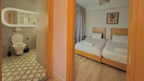 Ein Hotelzimmer mit Bad, einem Bett, einem Spiegel und einem Gemälde.