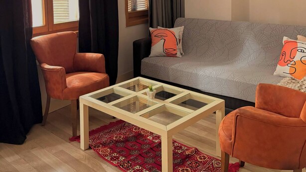 Ein Wohnzimmer mit einer Couch, zwei Sesseln, einem Couchtisch und einer Pendelleuchte.