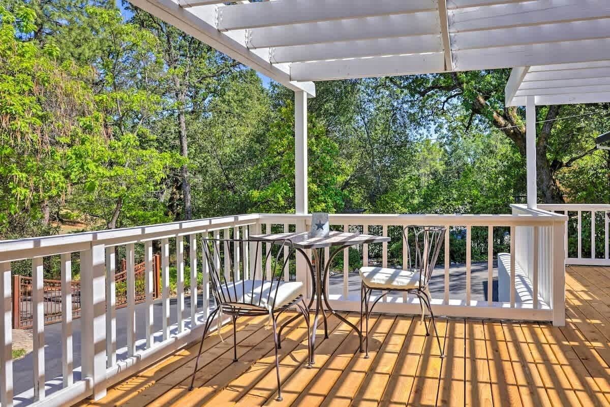 A wooden deck with a white railing, two metal chairs, and a small table.