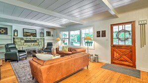 Un salon avec une cheminée, un canapé, une table basse et une porte au design rappelant celui d’une grange.