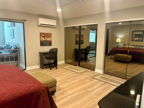 Ein Hotelzimmer mit einem Bett, einem Schreibtisch mit Stuhl, einem kleinen Tisch, einer Couch und einem Spiegel.