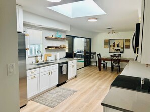 Eine moderne Küche mit weißen Schränken, einem eingebauten Backofen und einem Essbereich mit Tisch und Stühlen.