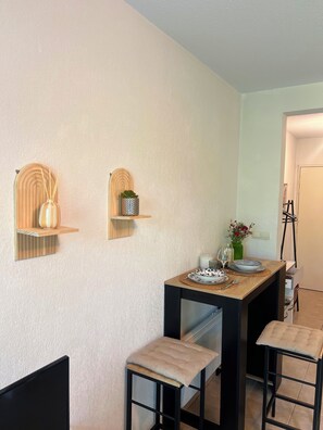 Un comedor con mesa de madera, dos sillas y estantes con adornos.