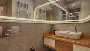 A bathroom with a white sink, a mirror with a light strip, a towel rack, and patterned floor tiles. - Taksim Square1 Bedroom Suite 06 (Istanbul)