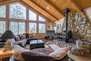 Ein gemütliches Wohnzimmer mit Kamin aus Stein, einem großen Fenster und einer bequemen Sitzecke.