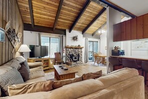 Ein gemütliches Wohnzimmer mit Kamin, Fernseher und Essbereich, im Hintergrund eine Küche.